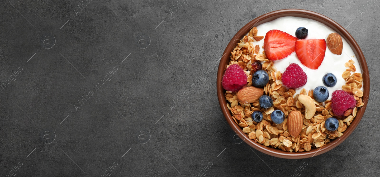 Image of Tasty homemade granola with berries served on grey table, top view with space for text. Banner design