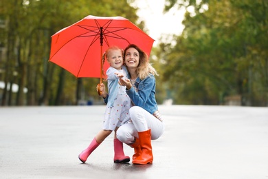 Photo of Happy mother and daughter with red umbrella on street