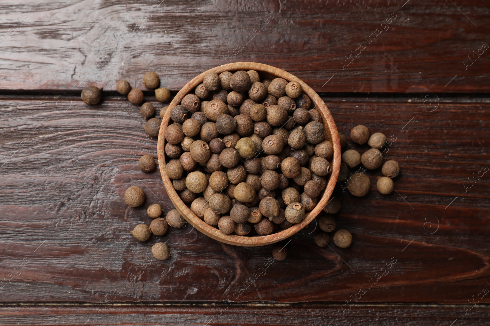 Photo of Dry allspice berries (Jamaica pepper) in bowl on wooden table, top view