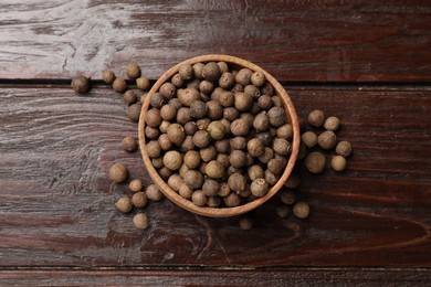 Dry allspice berries (Jamaica pepper) in bowl on wooden table, top view