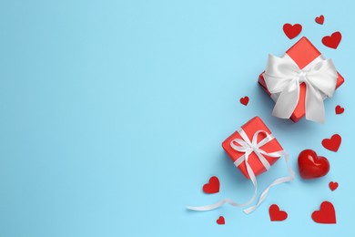 Photo of Beautiful gift boxes and red decorative hearts on light blue background, flat lay. Space for text