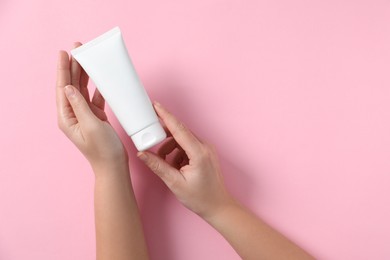 Woman with tube of hand cream on pink background, top view. Space for text