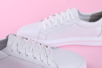 Photo of Pair of stylish white sneakers on pink background, closeup