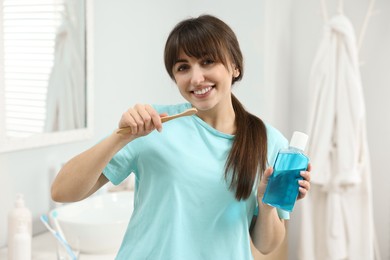Photo of Young woman with mouthwash and toothbrush in bathroom
