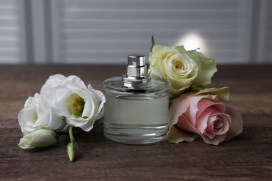 Photo of Bottle of perfume and flowers on wooden table indoors