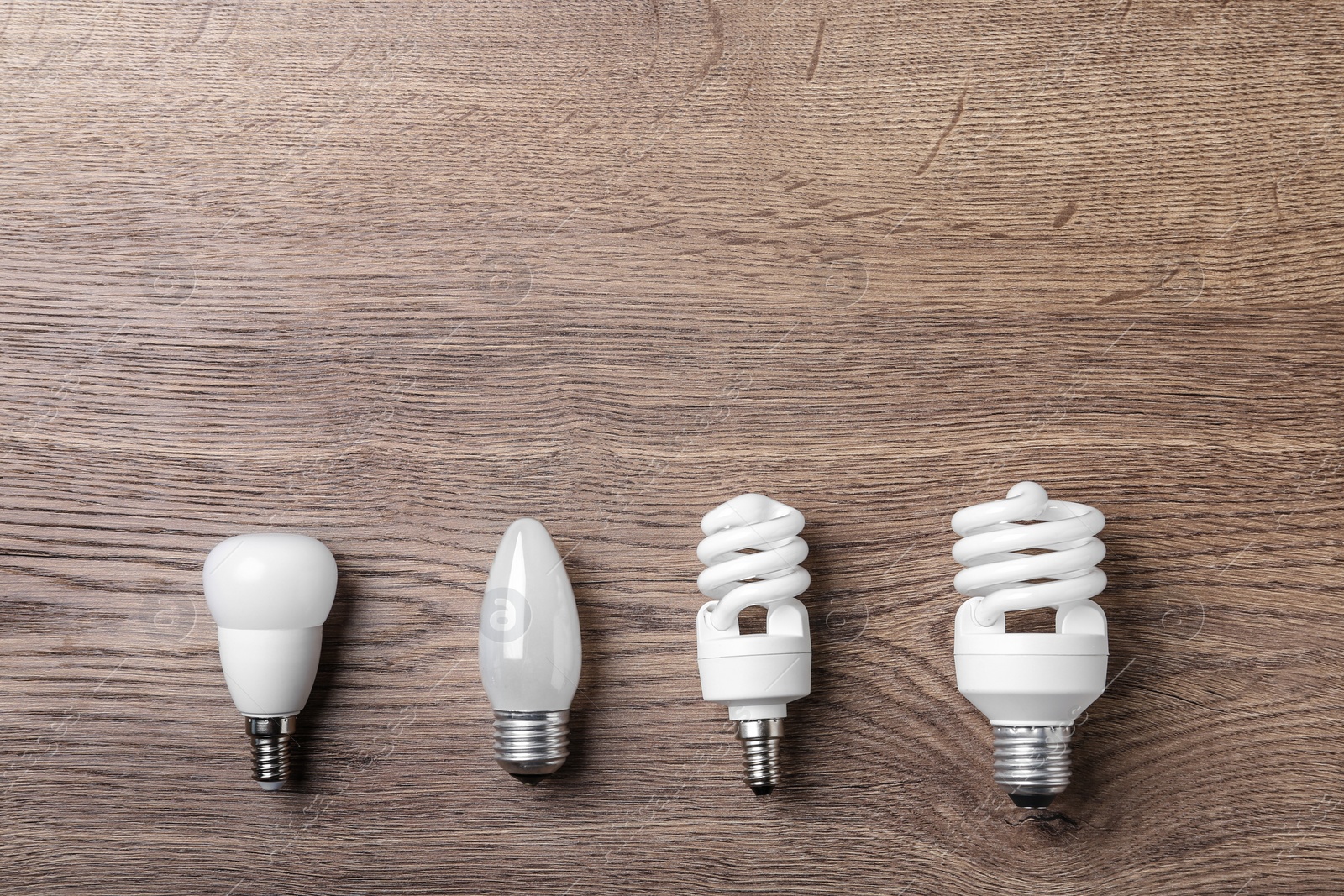 Photo of New fluorescent lamp bulbs on wooden background, flat lay. Space for text