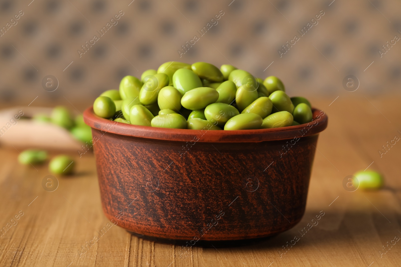 Photo of Bowl of delicious edamame beans on wooden table