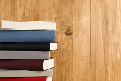 Photo of Stack of hardcover books on wooden background, space for text
