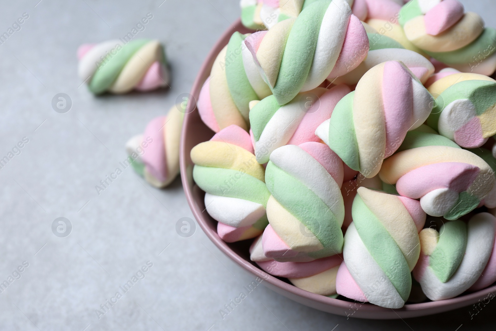 Photo of Bowl with colorful marshmallows on grey table, closeup