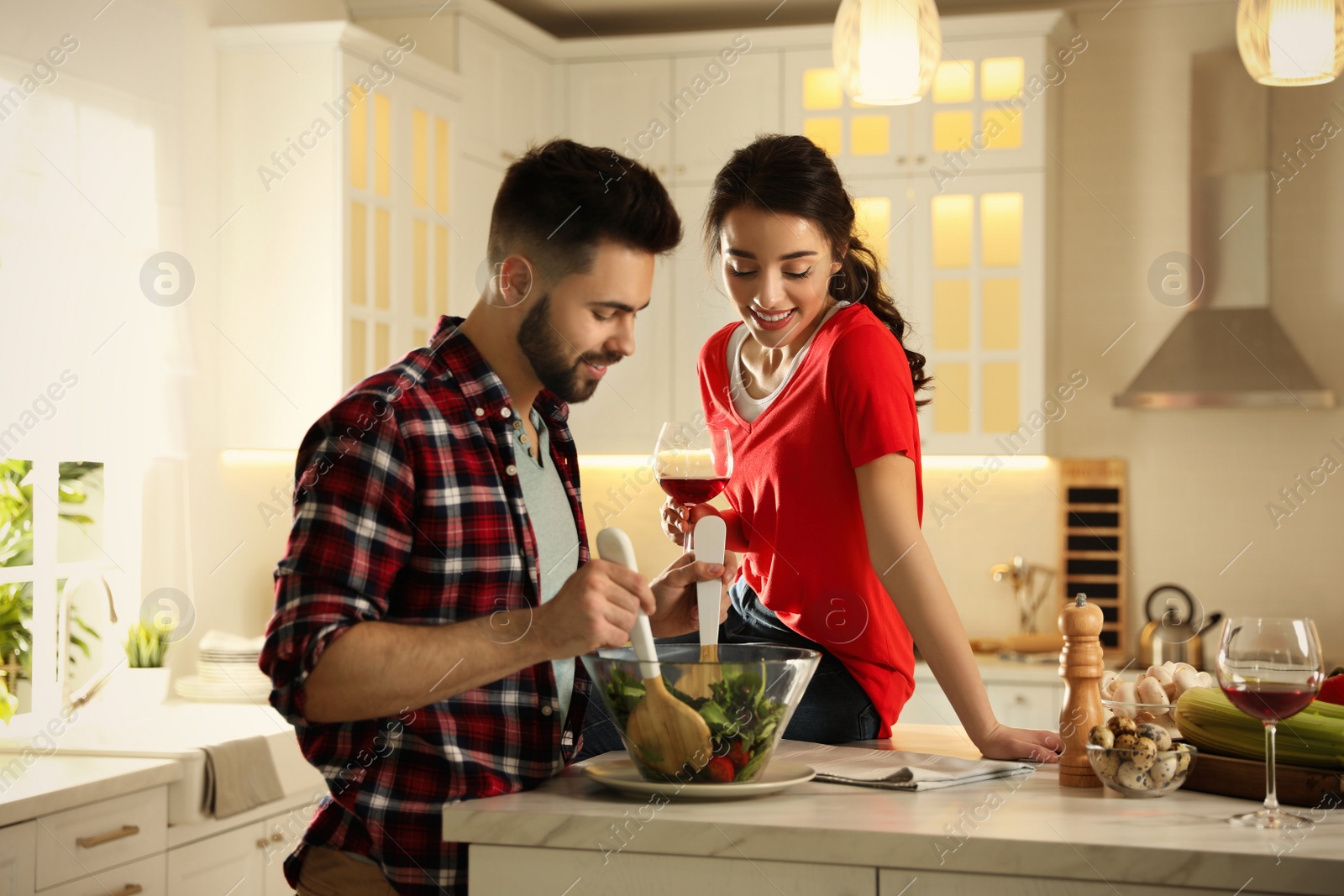 Photo of Lovely young couple cooking salad together in kitchen