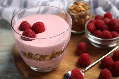 Photo of Tray with delicious yogurt, raspberries and granola on old wooden table, closeup