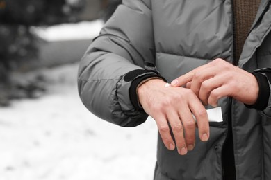 Photo of Man applying cream from tube onto hand outdoors, closeup. Winter care