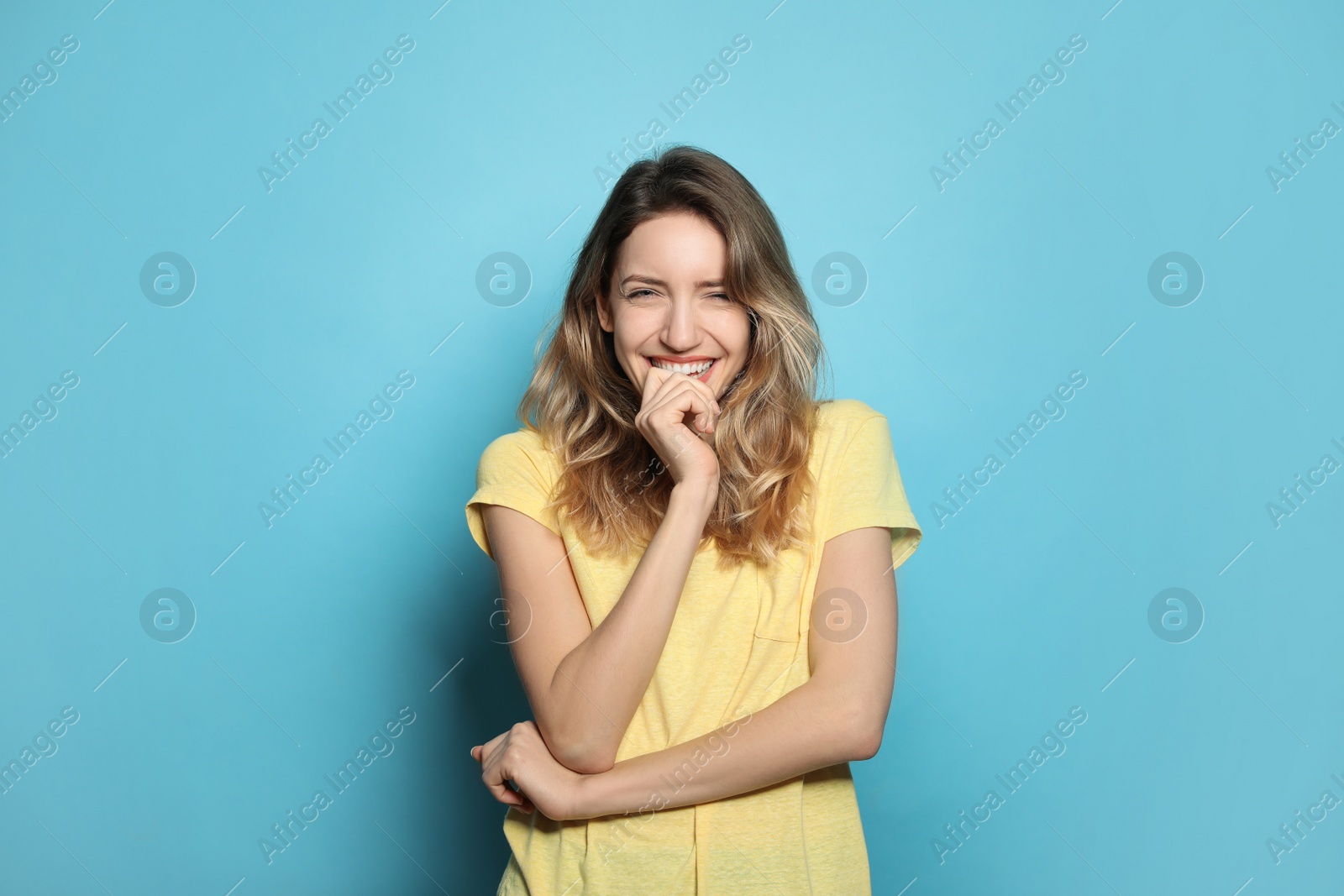 Photo of Cheerful young woman laughing on light blue background