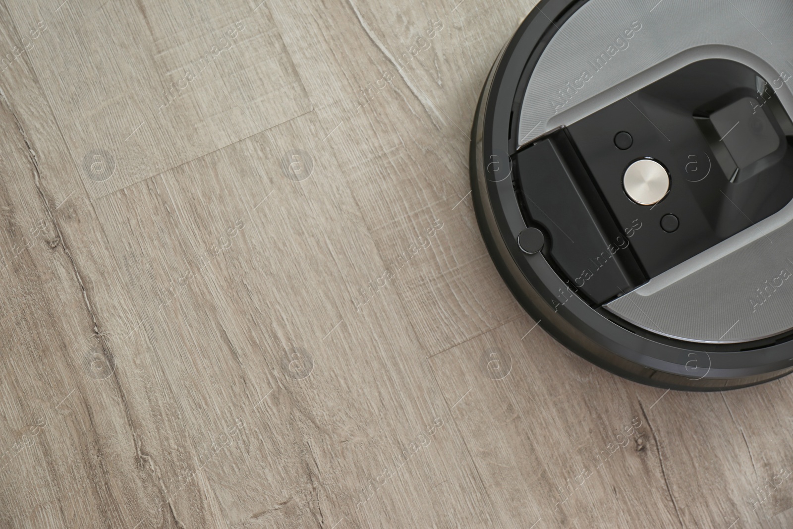 Photo of Modern robotic vacuum cleaner on wooden floor, top view. Space for text