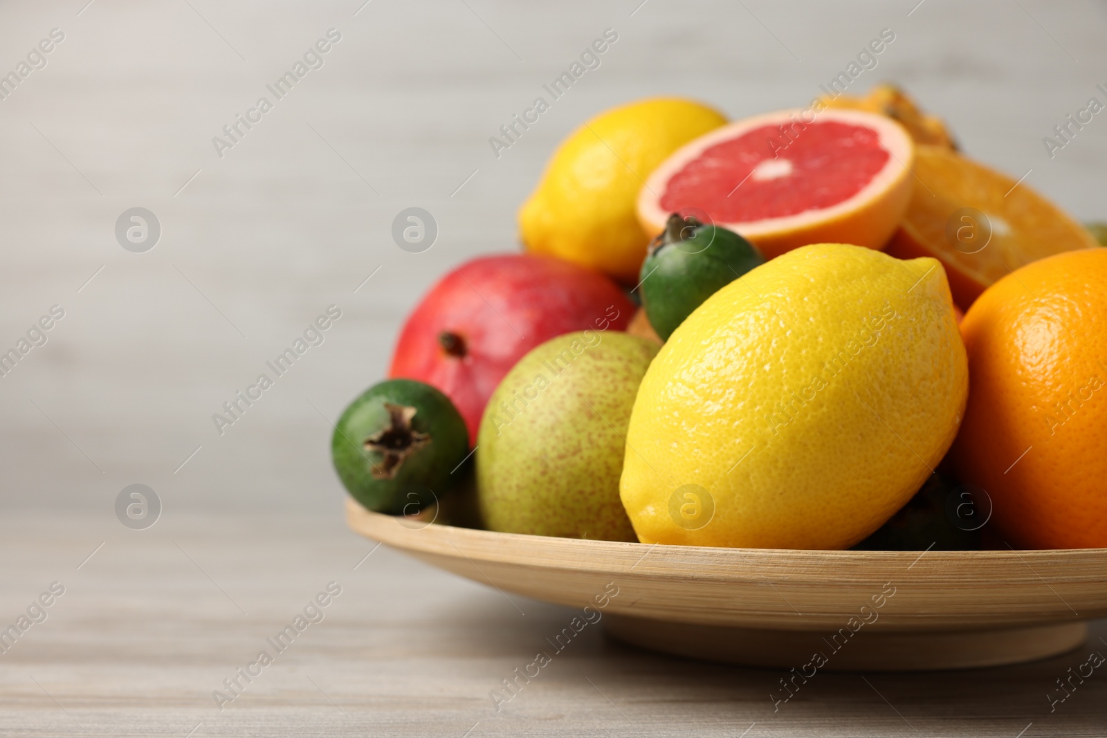 Photo of Different ripe fruits on light wooden table, closeup. Space for text