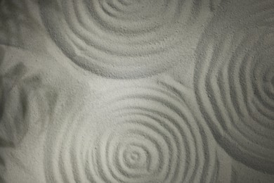 Beautiful spirals and shadows of leaves on sand, top view. Zen garden