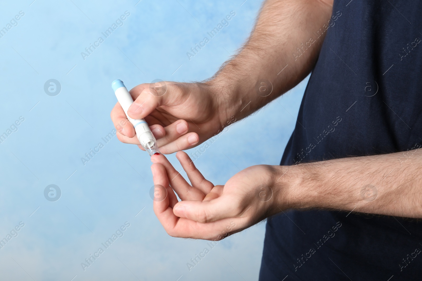 Photo of Man using lancet pen on color background. Diabetes test