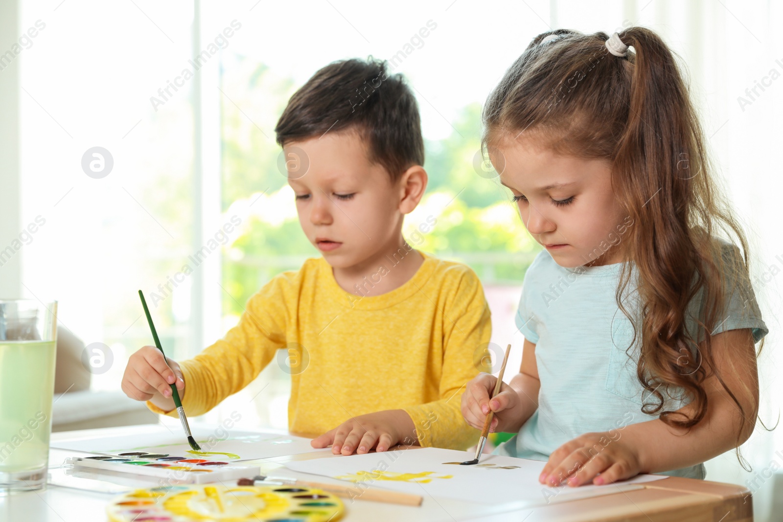 Photo of Cute little boy and girl drawing at table in living room