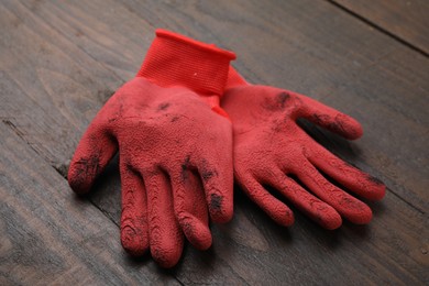 Photo of Pair of red gardening gloves on wooden table