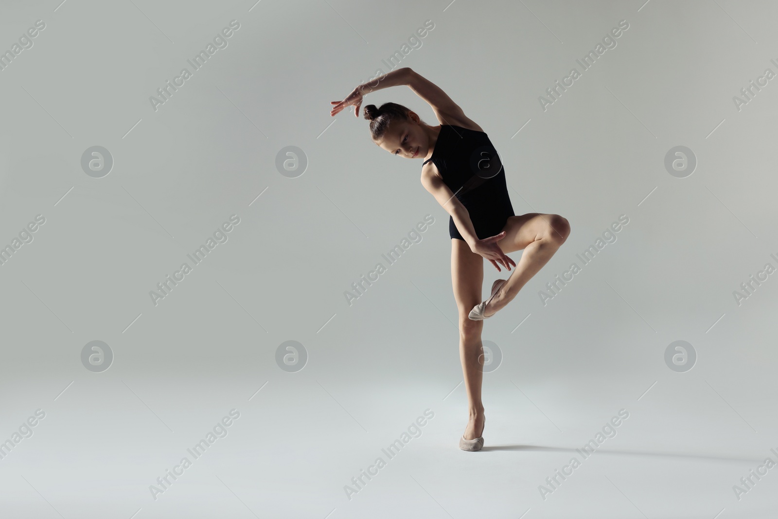 Photo of Cute little girl doing gymnastic exercise on white background