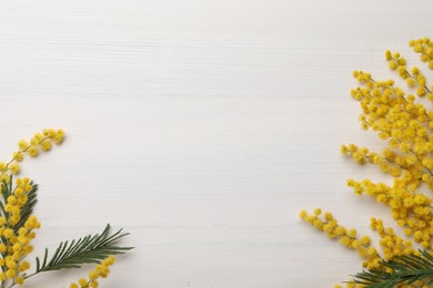 Beautiful mimosa flowers on white wooden table, flat lay. Space for text