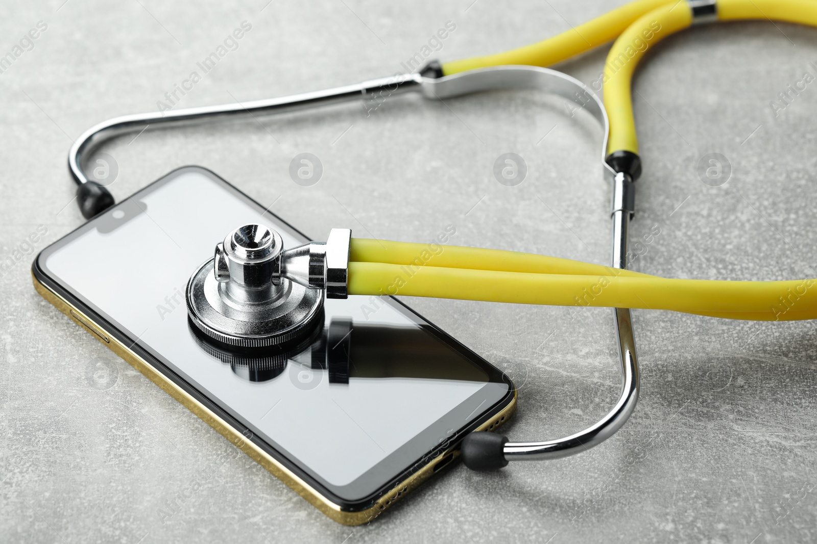 Photo of Stethoscope and modern smartphone on grey table