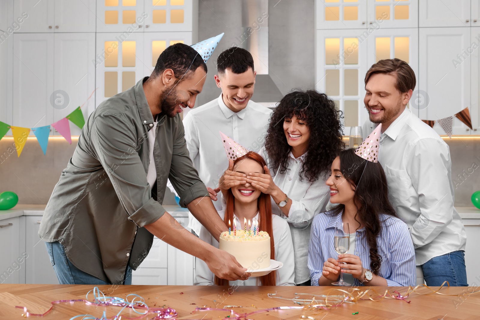 Photo of Happy friends with tasty cake celebrating birthday in kitchen