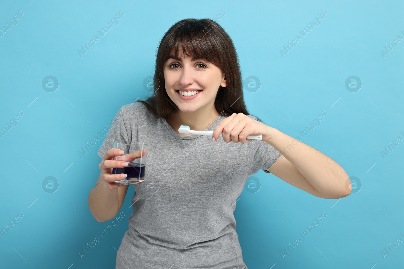 Photo of Young woman with mouthwash and toothbrush on light blue background