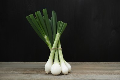 Photo of Bunch of fresh green spring onions on wooden table