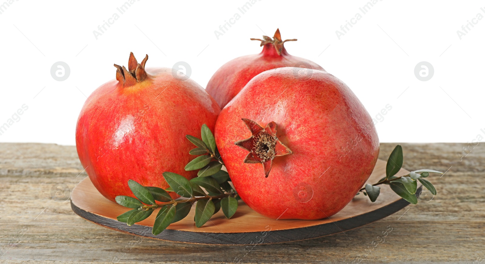 Photo of Fresh pomegranates and green leaves on wooden table against white background