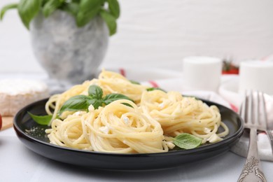 Delicious pasta with brie cheese and basil leaves on white table, closeup