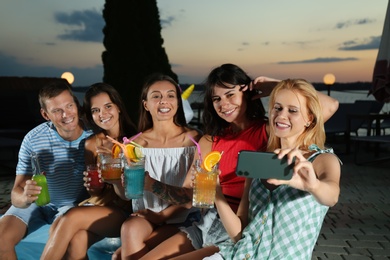 Photo of Happy people taking selfie at pool party in evening