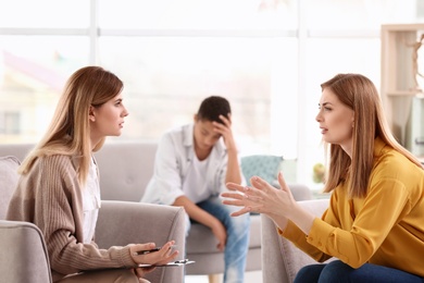 Photo of Young female psychologist working with teenage boy and his mother in office