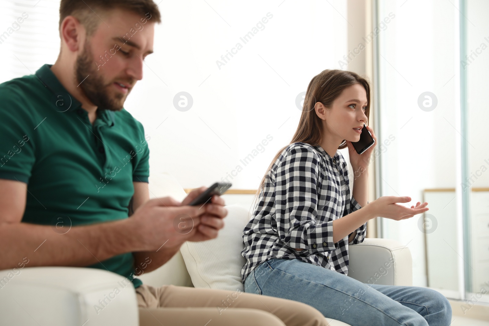 Photo of Couple addicted to smartphones ignoring each other at home. Relationship problems