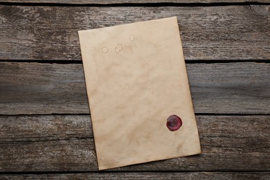 Photo of Sheet of old parchment paper with wax stamp on wooden table, top view. Space for design