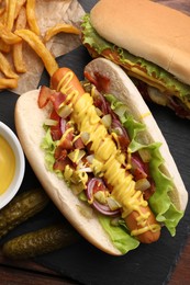 Delicious hot dogs with lettuce, onion and pickle served on table, flat lay