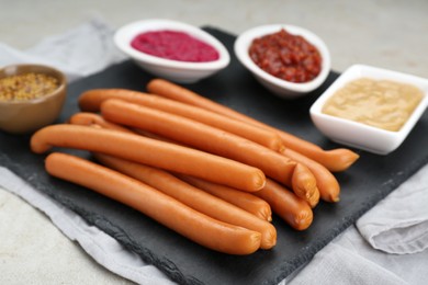Photo of Delicious sausages, ketchup, mustard and horseradish on grey table
