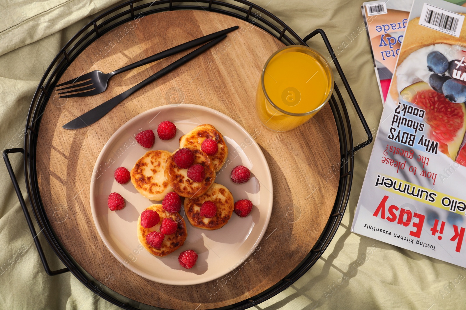Photo of Delicious cottage cheese pancakes with fresh raspberries and juice served on bed tray, flat lay