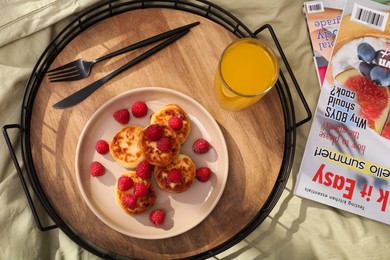 Delicious cottage cheese pancakes with fresh raspberries and juice served on bed tray, flat lay