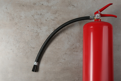 Fire extinguisher on light grey stone background, top view