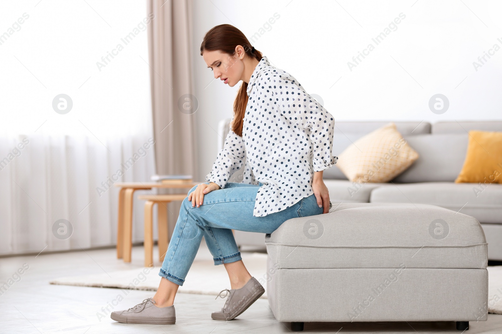 Photo of Young woman suffering from hemorrhoid at home