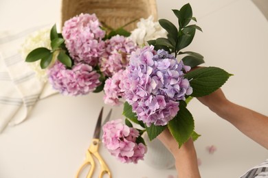 Photo of Woman making bouquet with beautiful hydrangea flowers indoors, top view. Interior design element