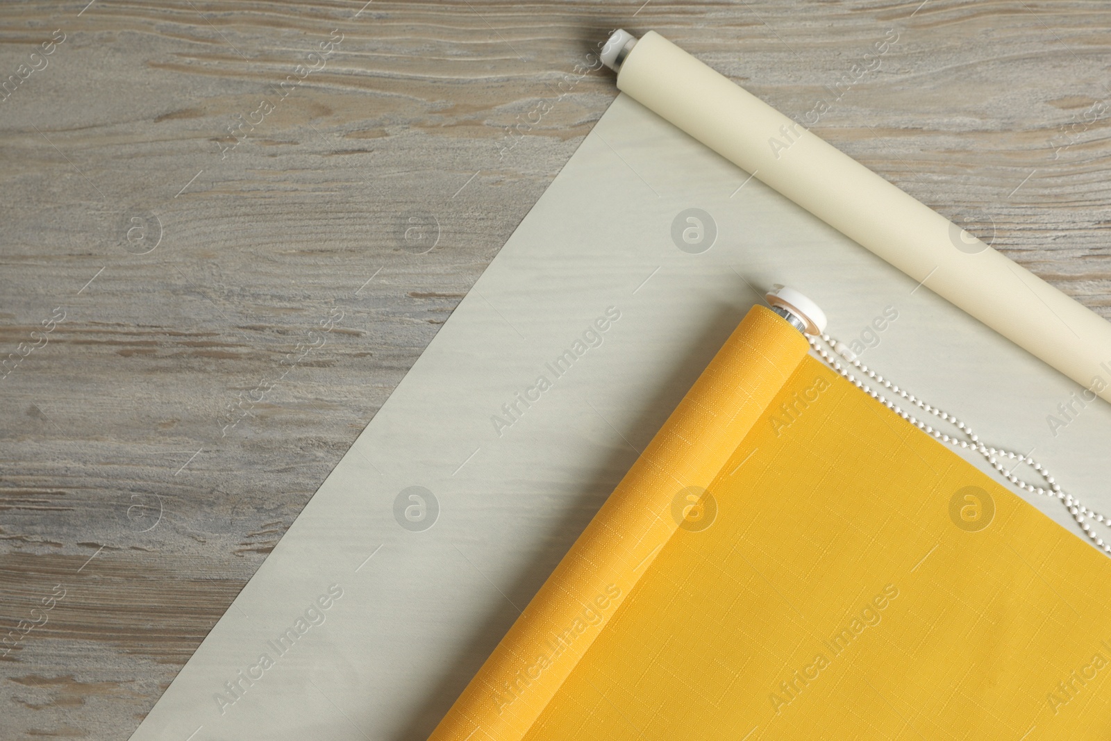 Photo of Stylish roller window blinds on wooden table, flat lay. Space for text