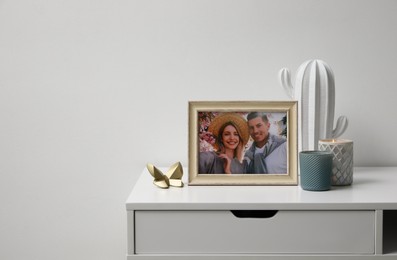 Framed photo of happy couple and candles on white table indoors. Space for text