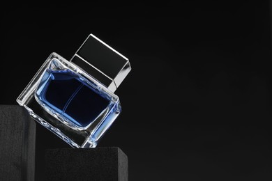 Luxury men`s perfume in bottle against dark background, space for text