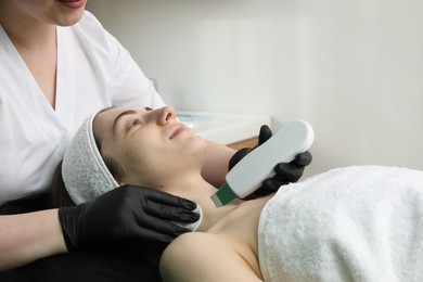 Photo of Cosmetologist using ultrasonic scrubber, closeup. Client having cleansing procedure in clinic