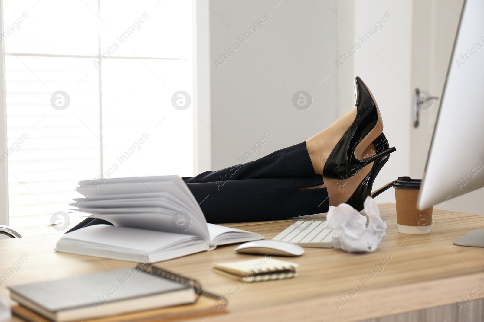 Photo of Lazy employee resting at table in office, closeup of legs