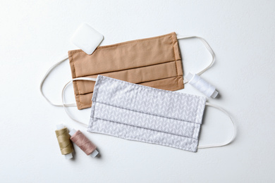 Homemade protective masks, threads and tailor's chalk on white background, flat lay. Sewing idea