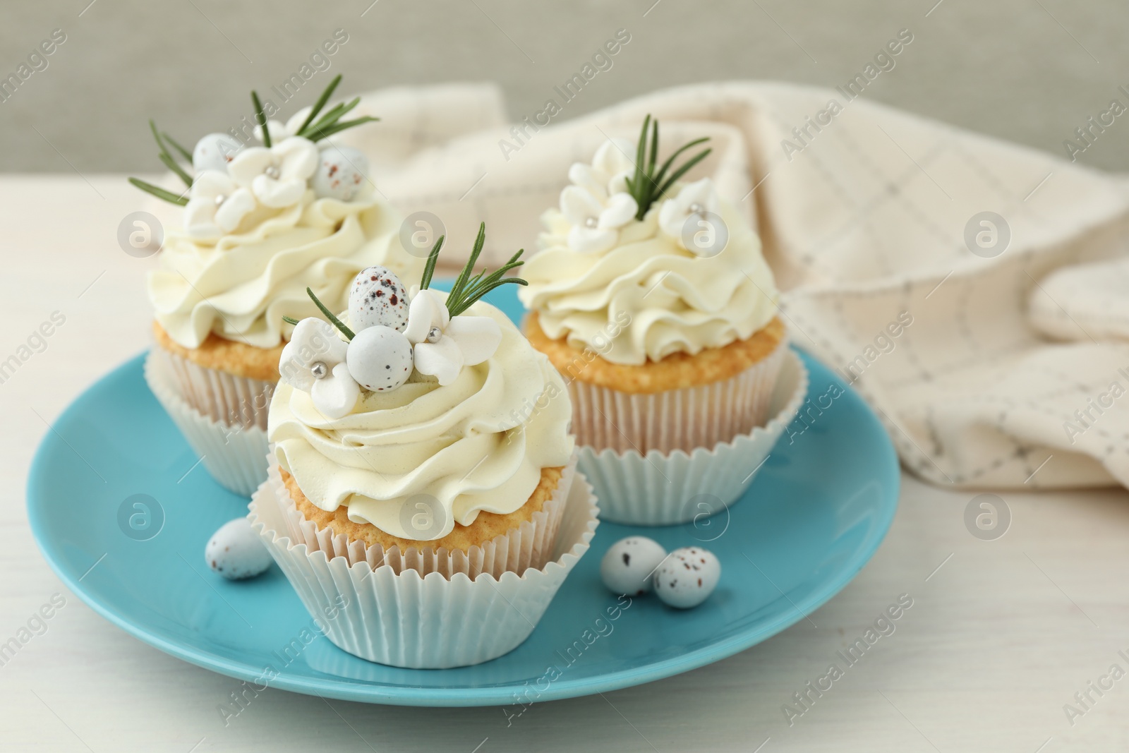 Photo of Tasty Easter cupcakes with vanilla cream on light wooden table, closeup