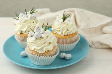 Tasty Easter cupcakes with vanilla cream on light wooden table, closeup